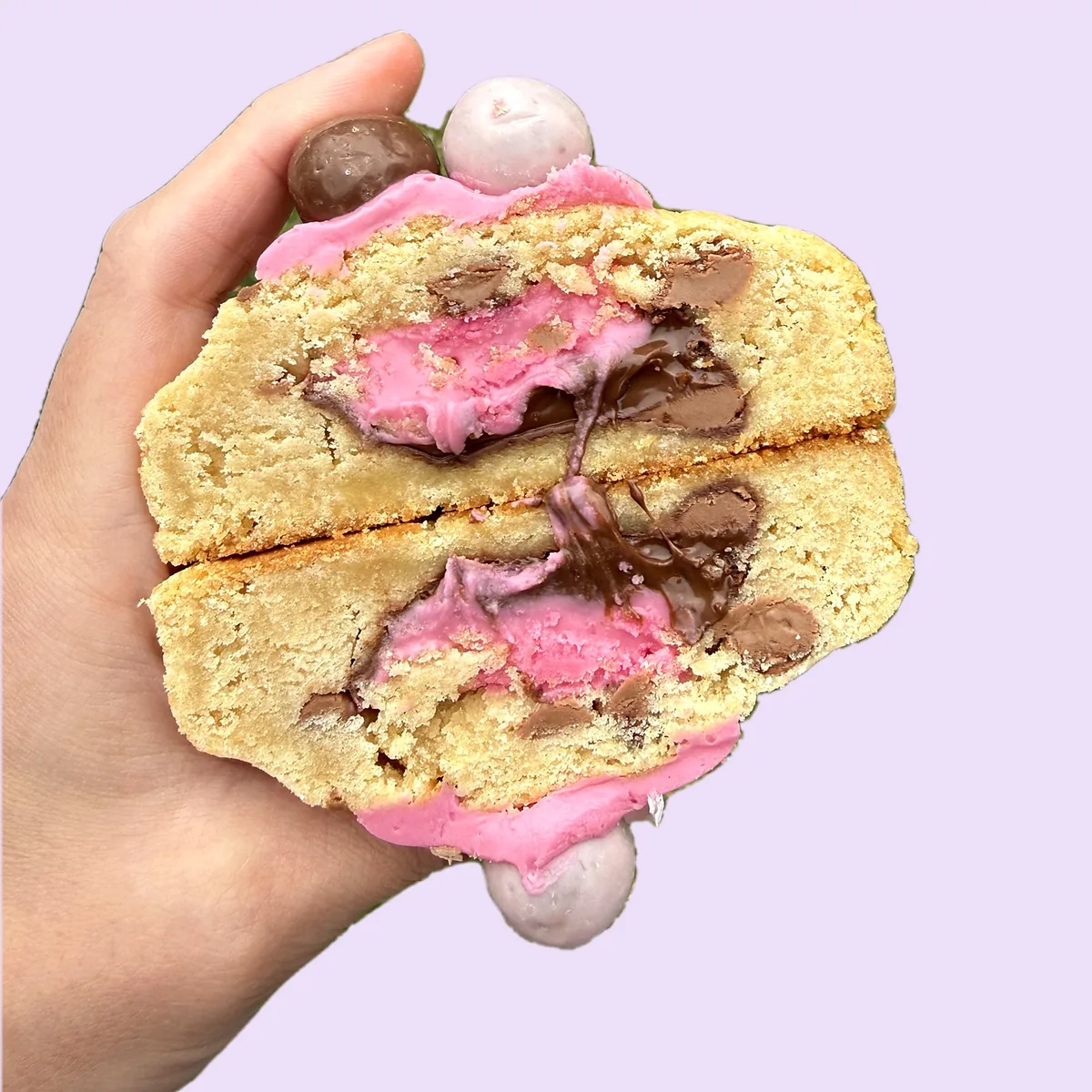 Malteser Strawberry Nutella cookie cut in half, showing strawberry spread and Nutella in the middle, topped with two Maltesers