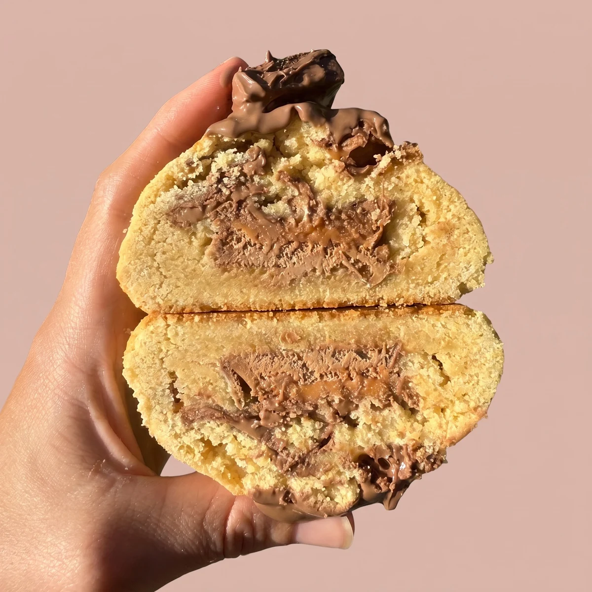Mars Bar cookie cracked in half, chunks of Mars Bar through the crumb with caramel and chocolate running from the centre