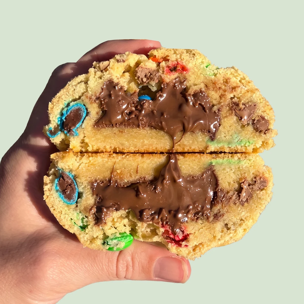 M&M Nutella cookie cracked in half, molten Nutella running from the core with bright M&M's set through the crumb