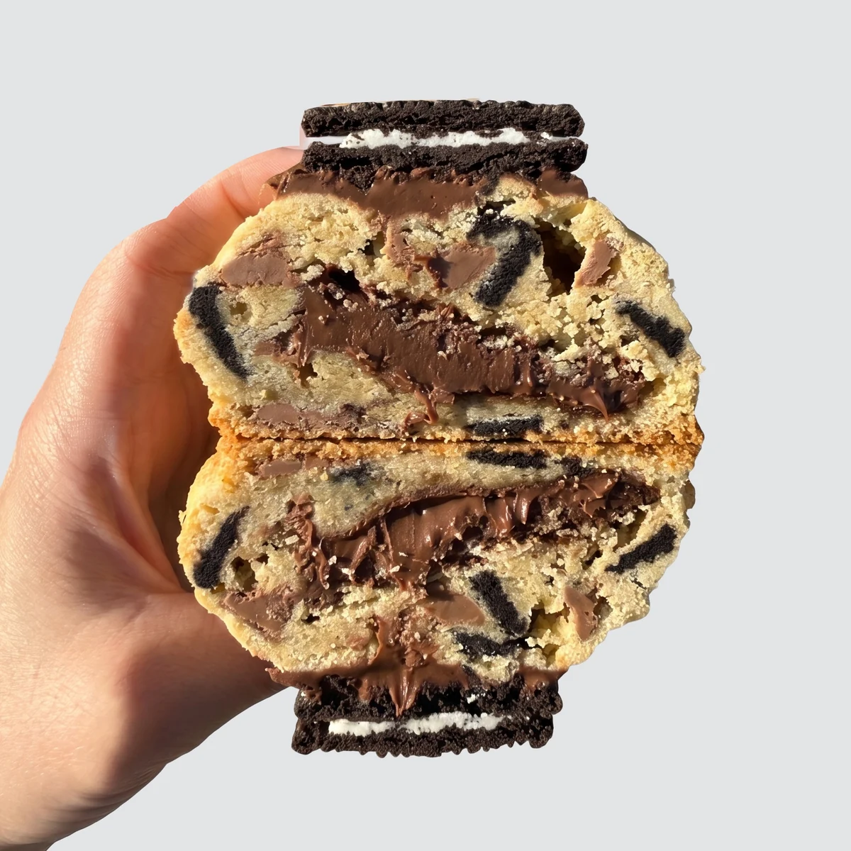 Oreo cookie cracked in half, molten Nutella running through a golden crumb shot through with Oreo pieces, a whole Oreo on top